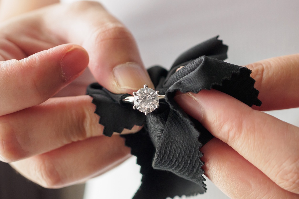 Jeweller cleaning jewelry diamond ring with fabric cloth