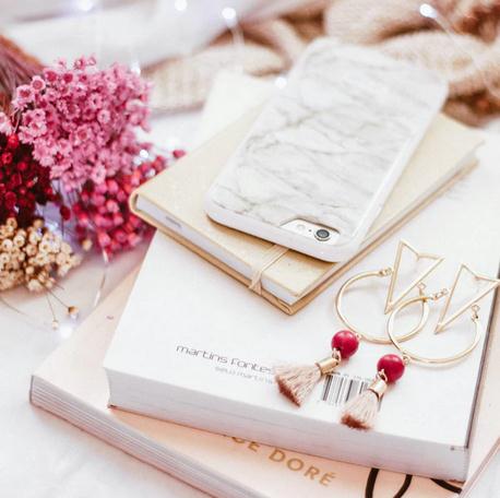 Image of an iPhone beside rose-gold earrings