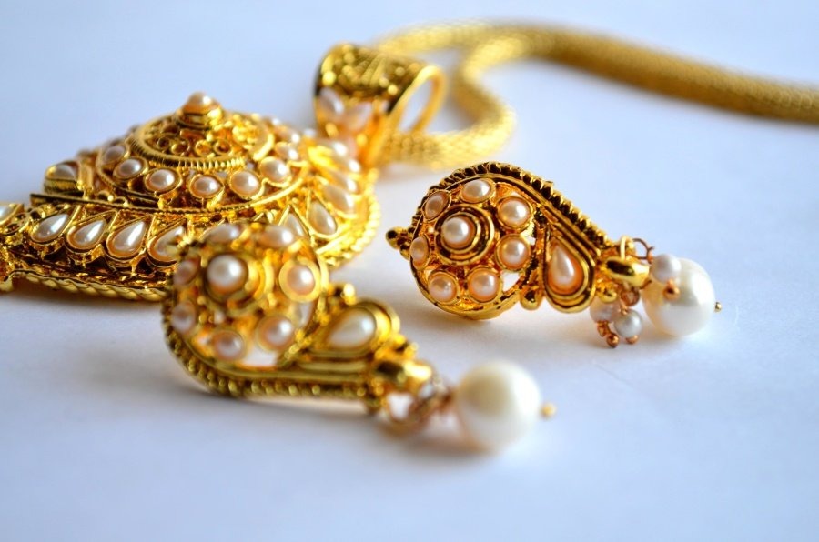 A set of ornate gold necklace and gold earrings embedded with pearls