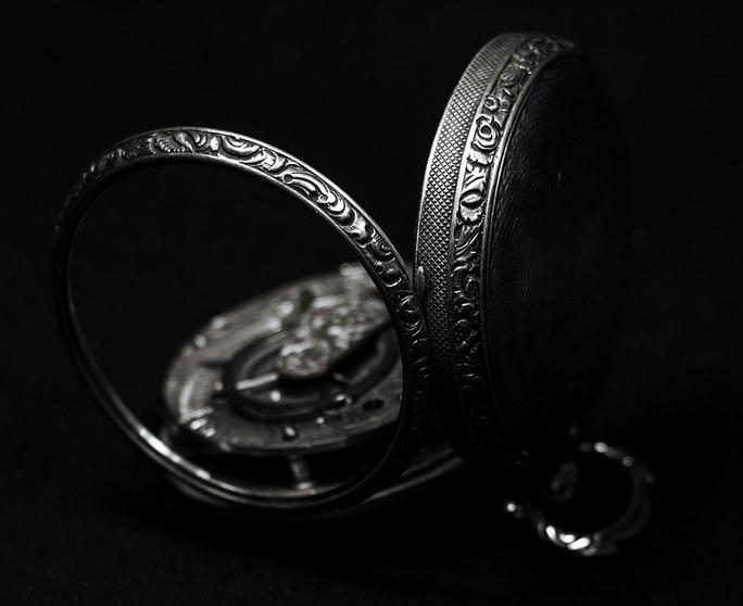 Picture of a jewelry pocket watch with engraved impressions in a dark light setting