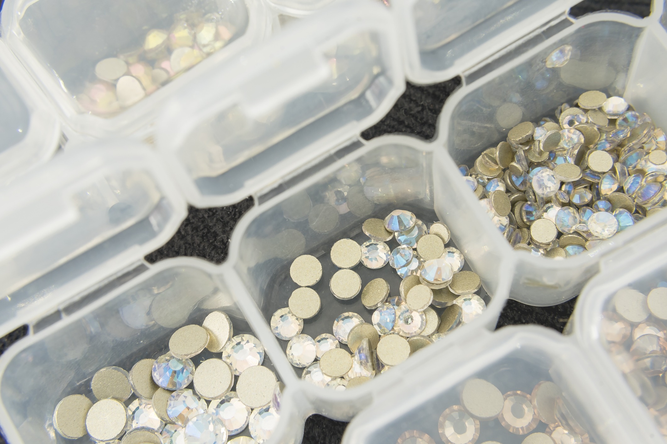 Various nail art rhinestones and accessories neatly organized in clear containers.