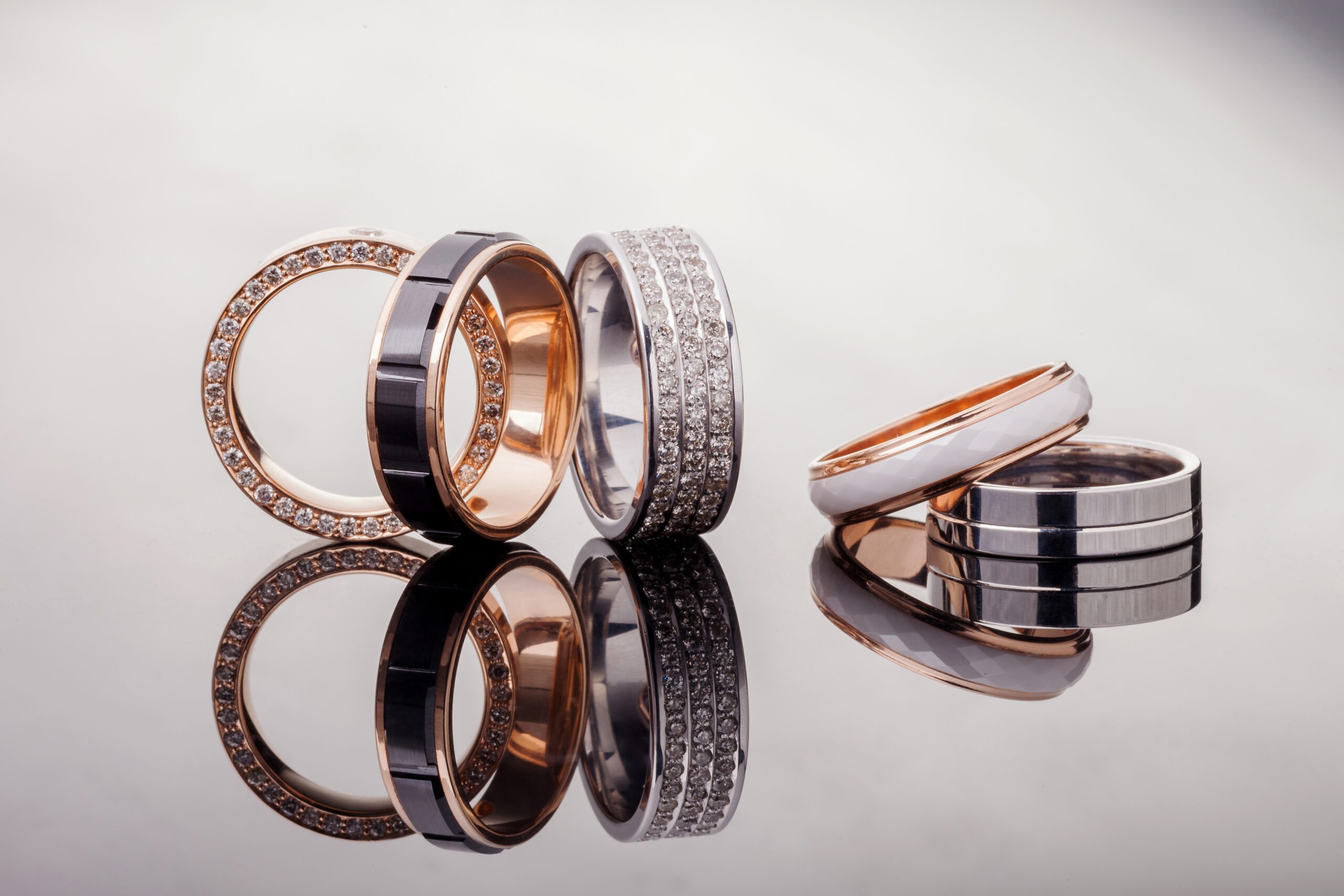 silver-gold-platinum-rings-of-different-styles-on-the-gray-background-of-reflections